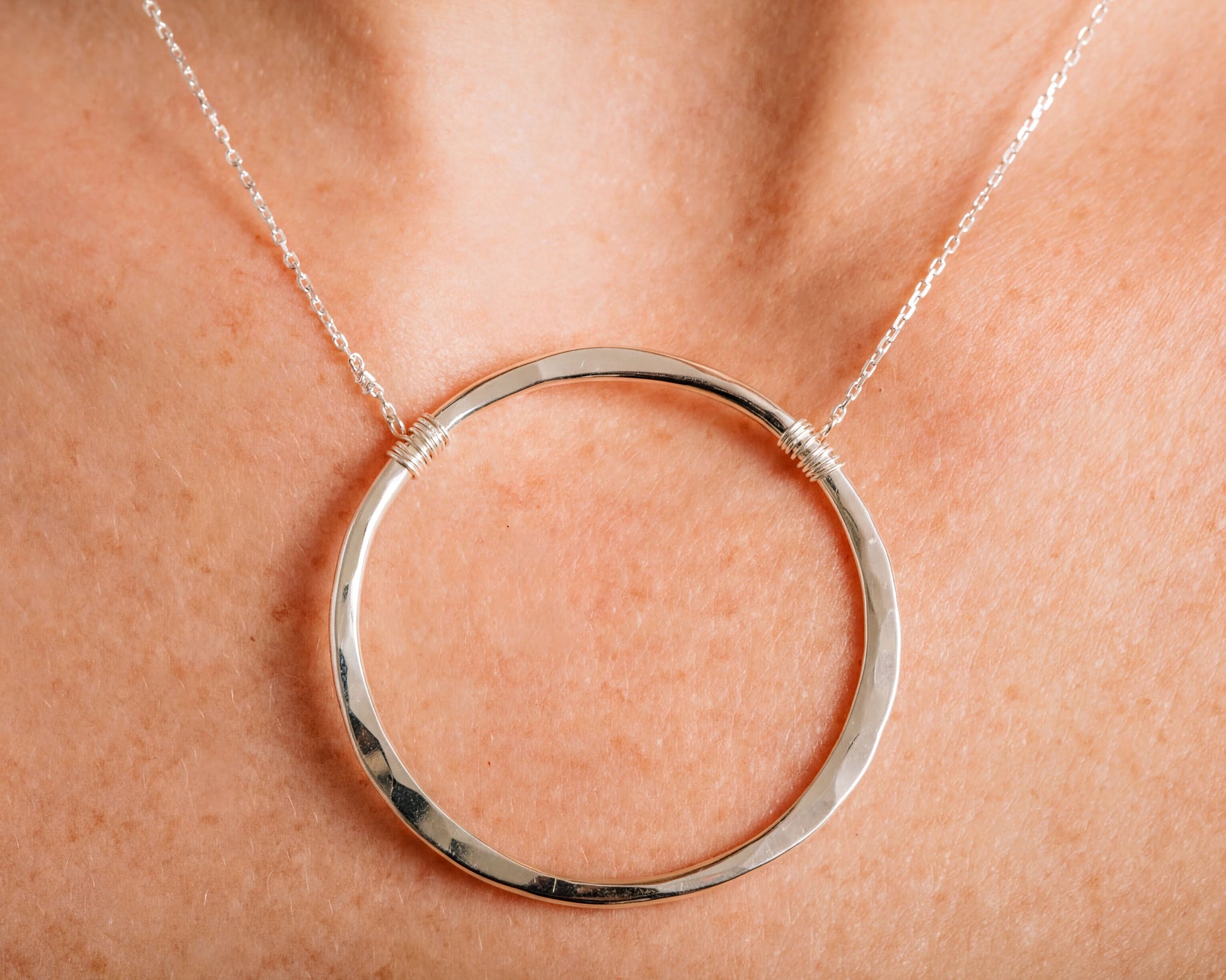 A close-up view of a silver necklace with a large circular pendant.