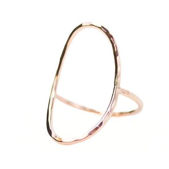 A gold-colored ring with a unique, irregular shape resembling a crescent moon or an oval.