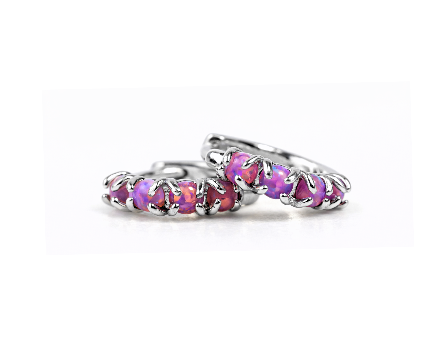 A pair of silver hoop earrings with a row of purple gemstones or stones.