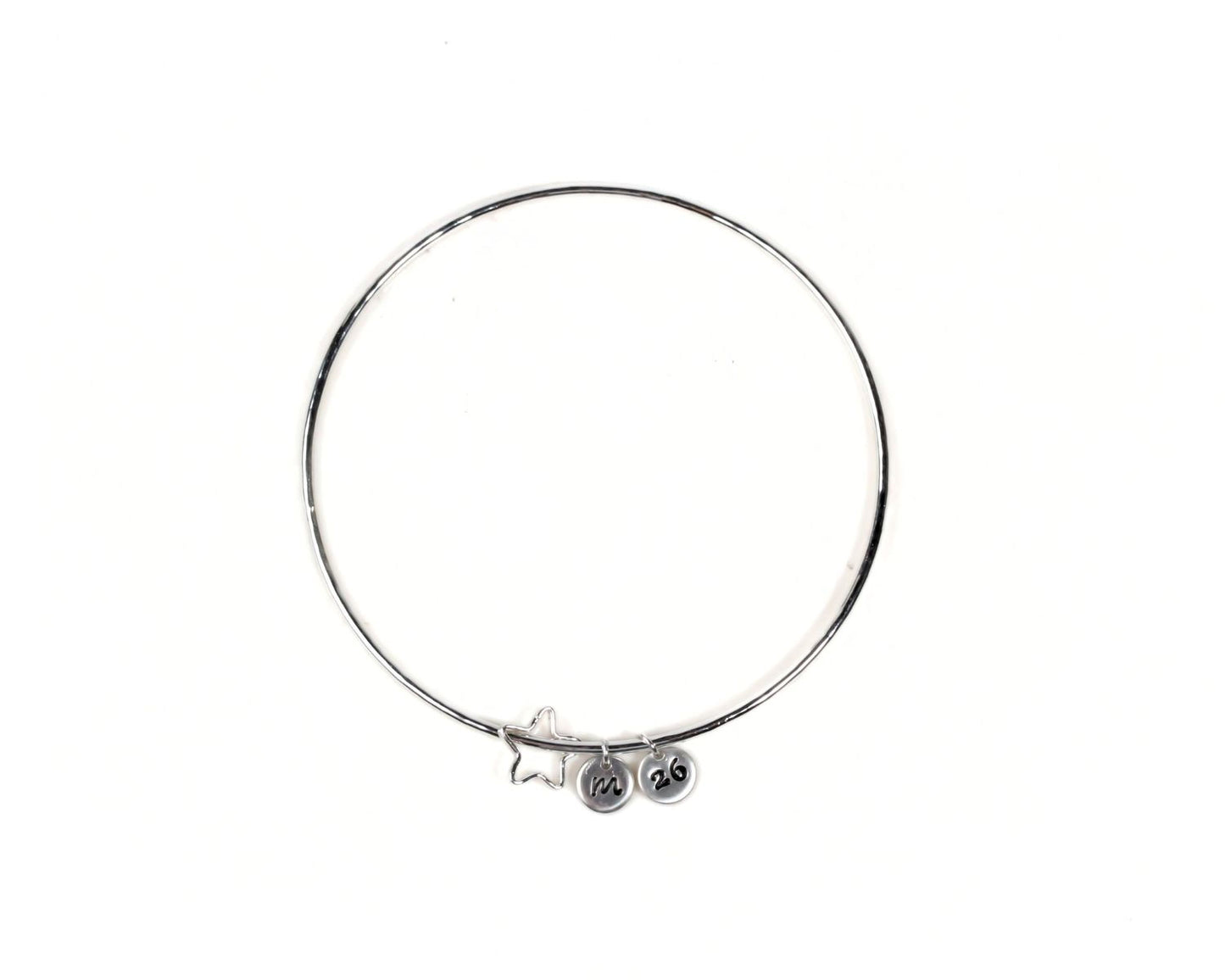 A silver-colored bangle bracelet with charms hanging from it.