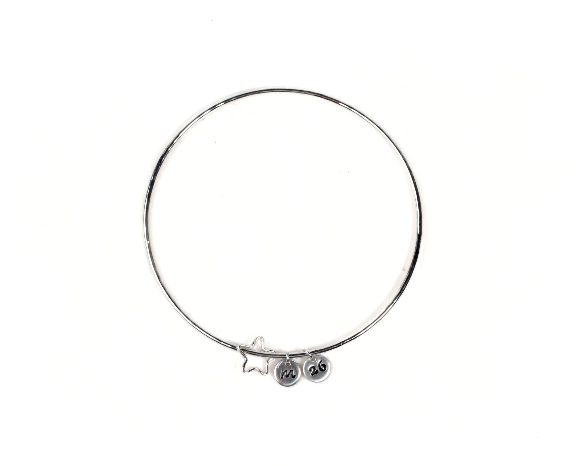 A silver-colored bangle bracelet with charms hanging from it.