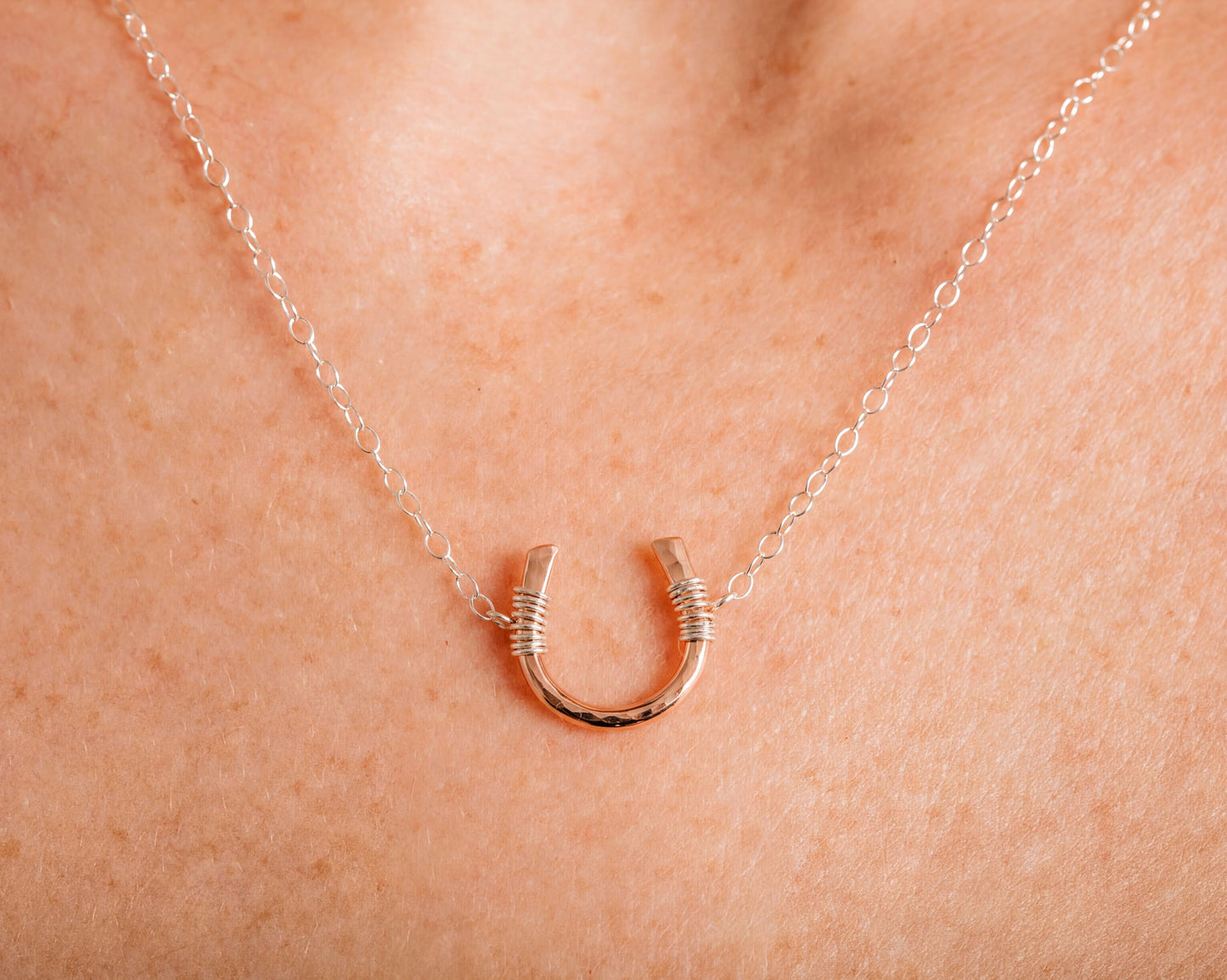 A delicate necklace with a small, intricately designed horseshoe pendant.