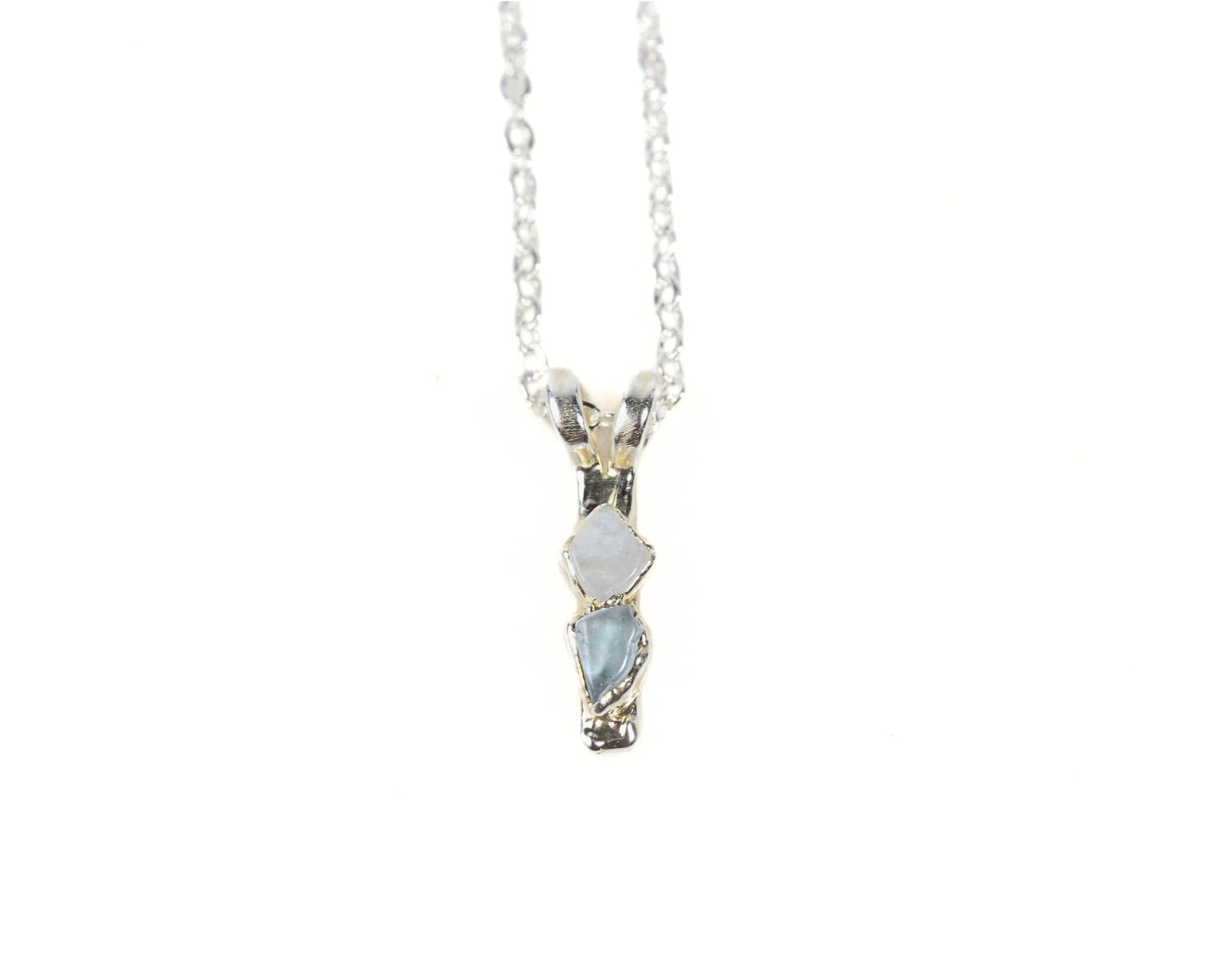 A silver necklace with a pendant featuring two blue gemstones.