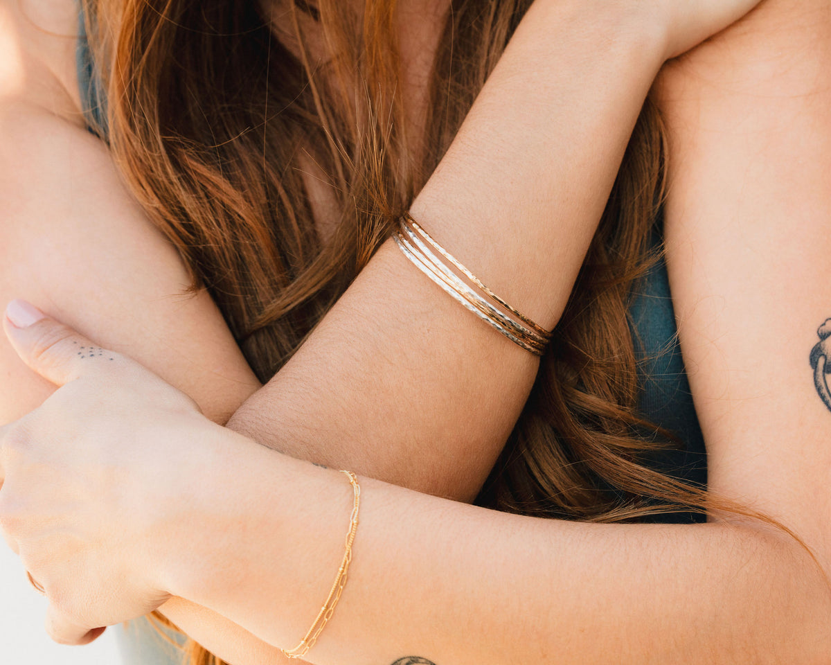 A close-up image of two people embracing each other, with one person wearing a bracelet and the other person having a tattoo.