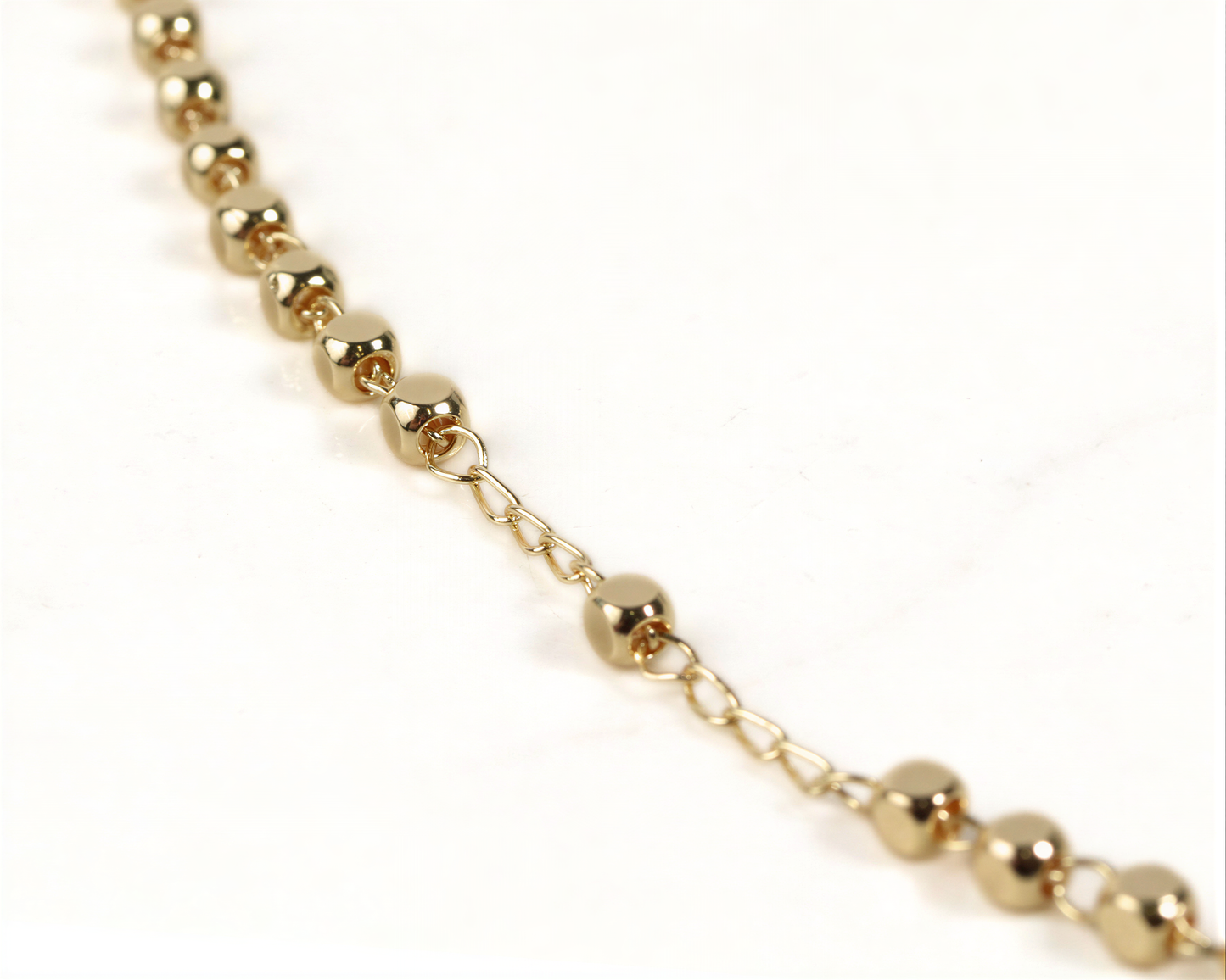 A close-up view of a gold-colored necklace with small, round beads attached to it.