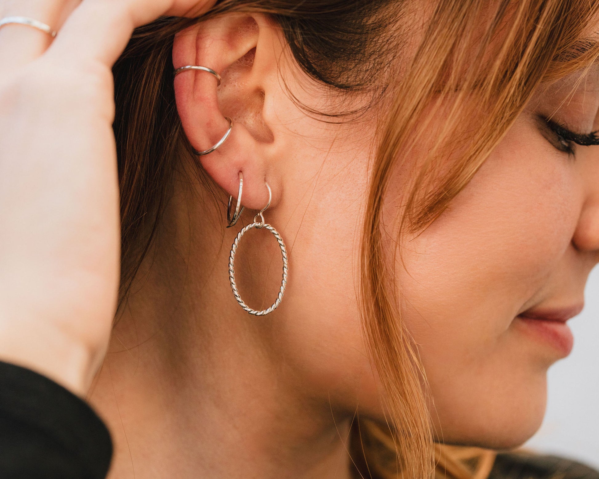 A close-up of a person's face, focusing on their earrings and hair.