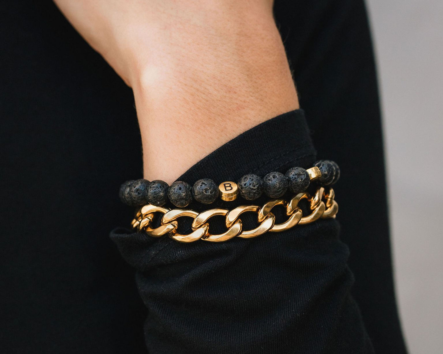 A close-up view of a person's wrist wearing two bracelets, one made of beads and the other a gold chain bracelet.