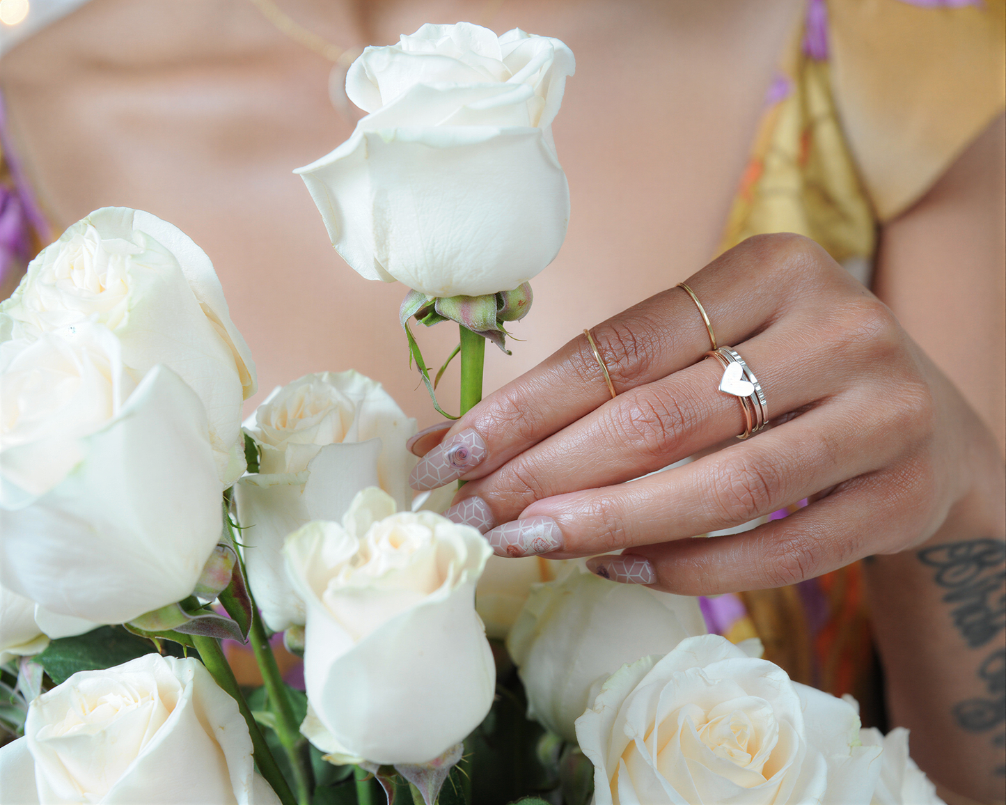 A close-up of a person's hand holding a bouquet of white roses, with a ring visible on one of the fingers.