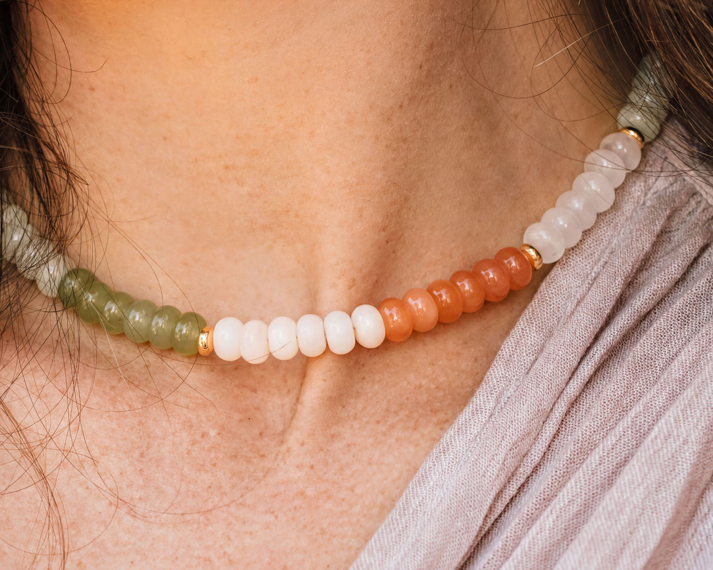 A close-up view of a person's neck wearing a colorful beaded necklace with green, white, and orange beads.