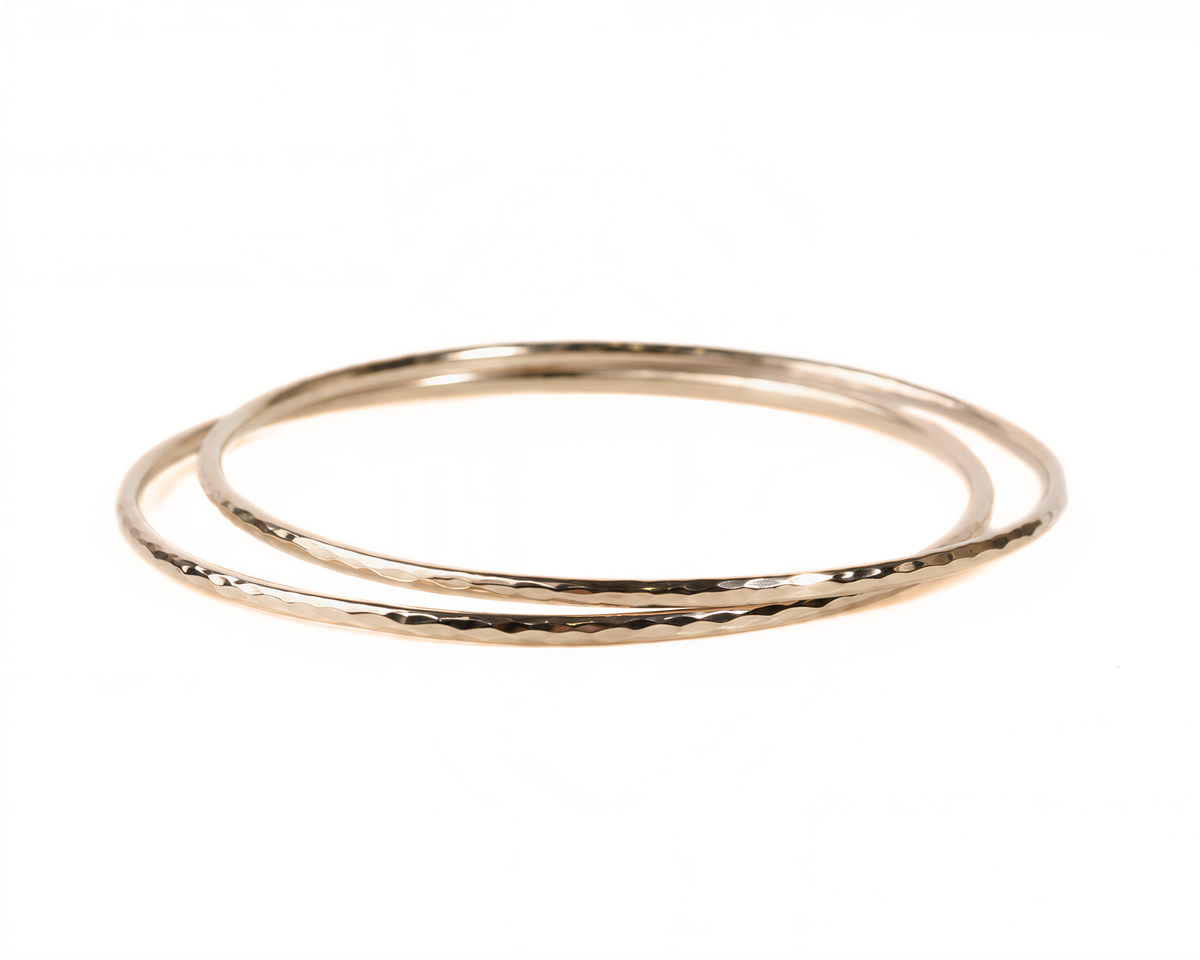 A pair of gold-colored, textured bangles arranged in a circular pattern against a white background.