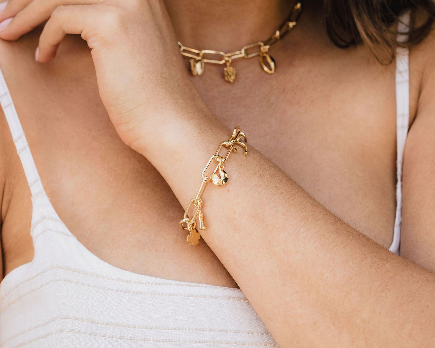A close-up view of a person's arm wearing a gold-colored bracelet and necklace.