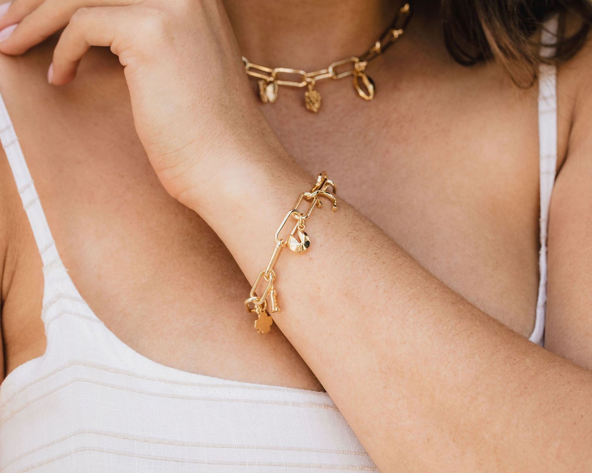 A close-up view of a person's arm wearing a gold-colored bracelet and necklace.