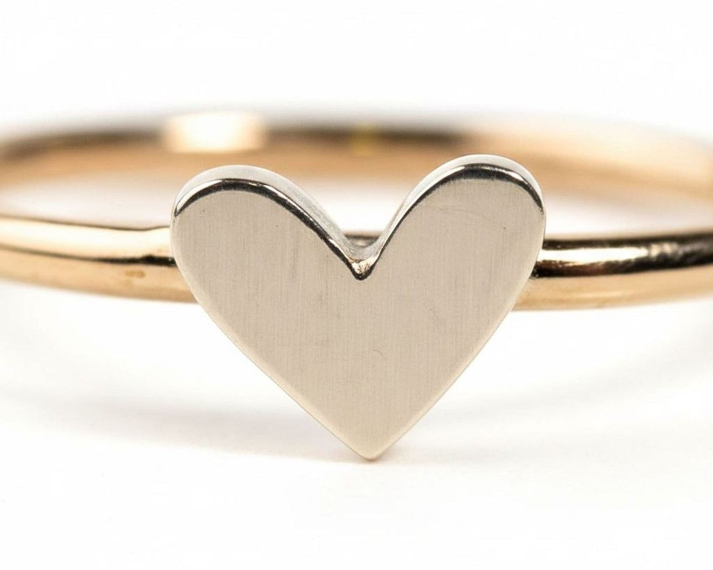 A close-up image of a gold ring with a heart-shaped charm in the center.