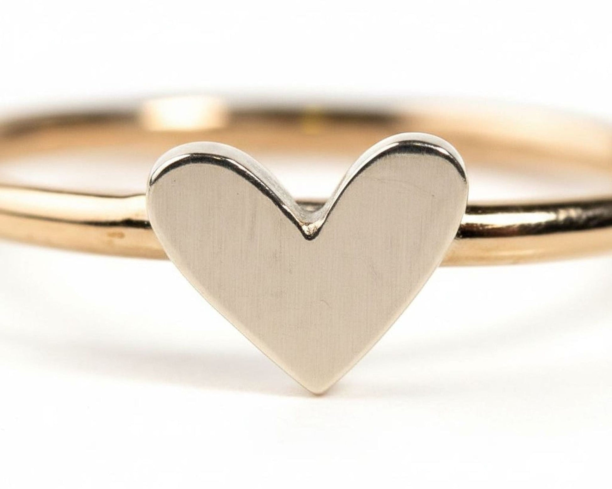 A close-up image of a gold ring with a heart-shaped charm in the center.