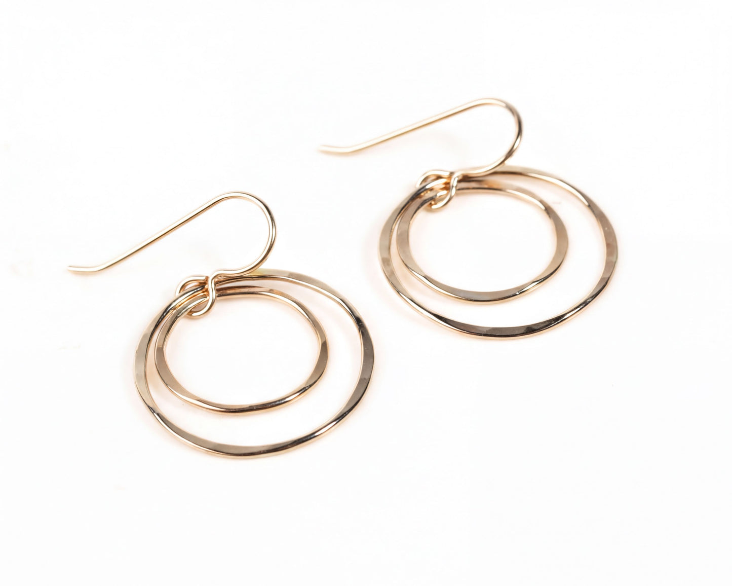 A pair of gold-colored earrings with two overlapping circular hoops.