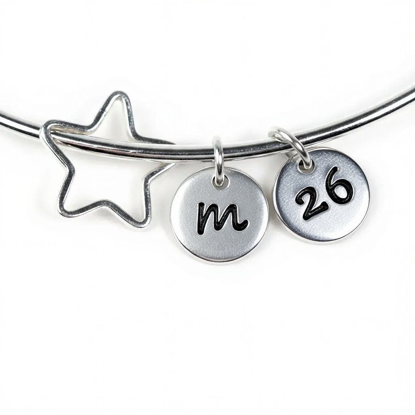 A silver bracelet with a star-shaped charm and two metal charms attached to it, each with a number on it.