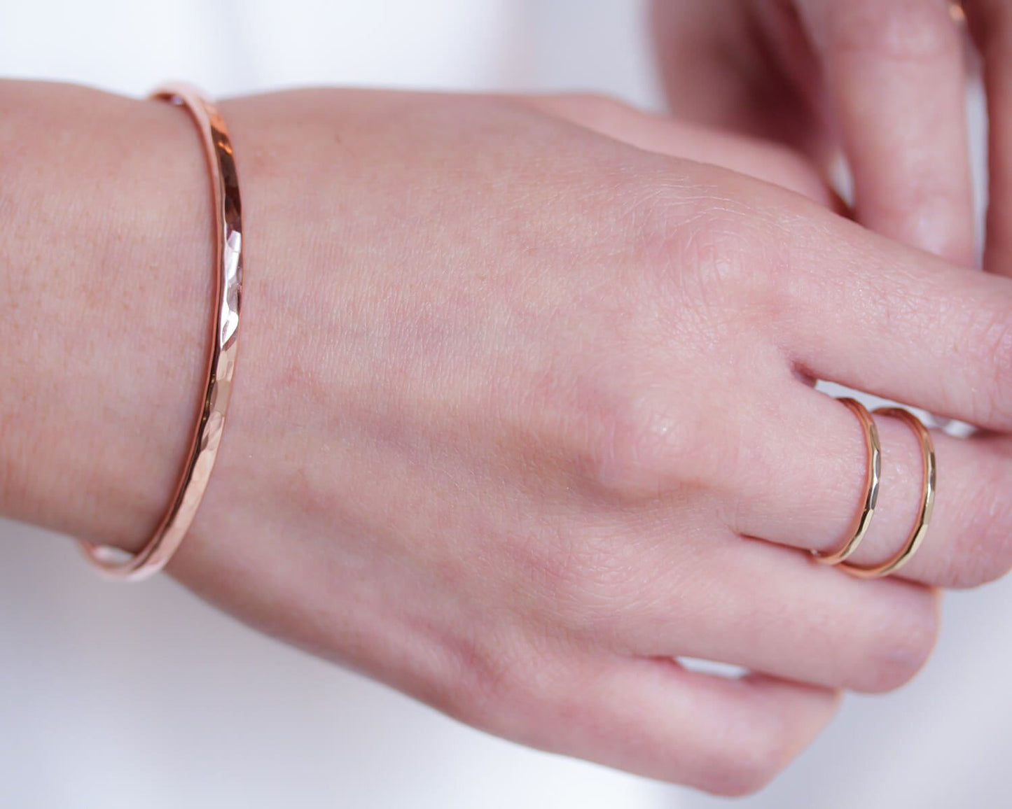 A close-up view of a person's hand wearing a copper-colored bracelet and a ring on one of the fingers.