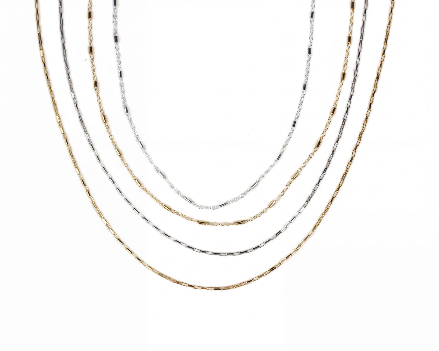 a collection of five different colored metal chain necklaces arranged in a row.
