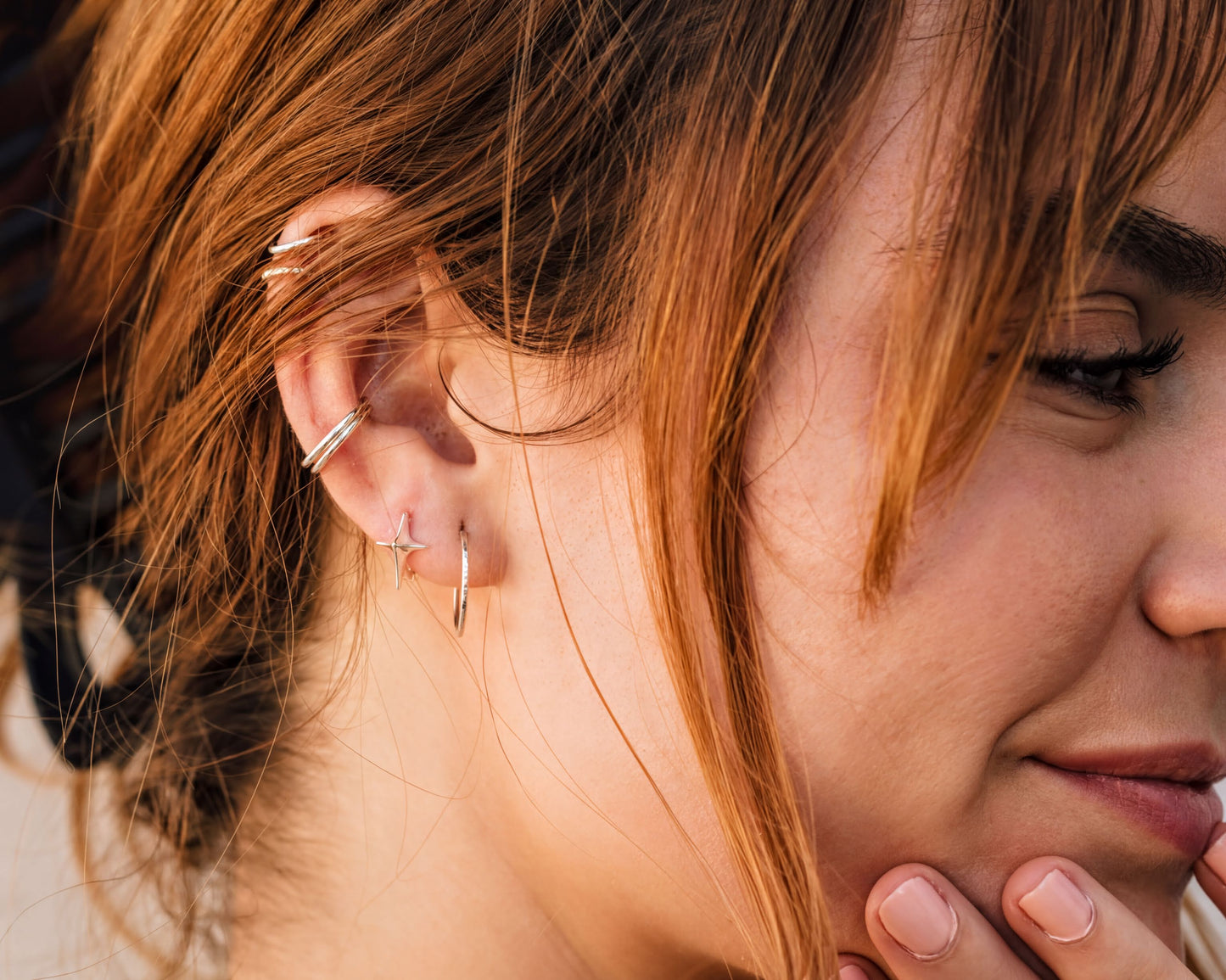 A close-up of a person's face, focusing on their earrings and hair.