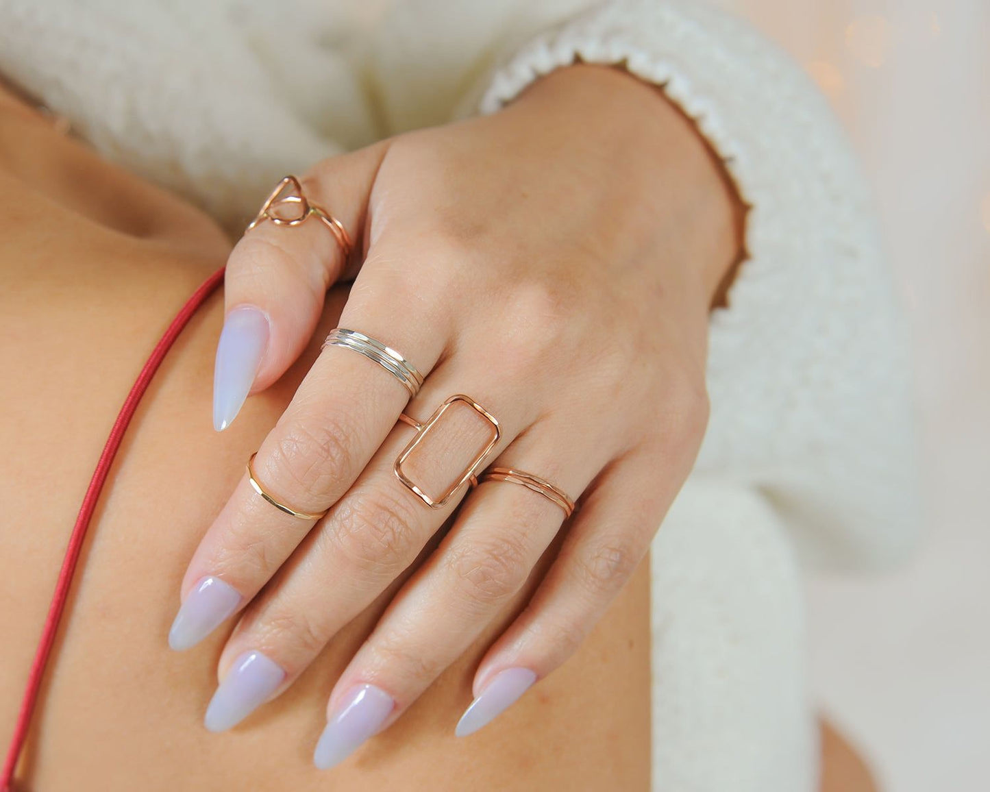 A close-up of a person's hand wearing multiple rings on their fingers.