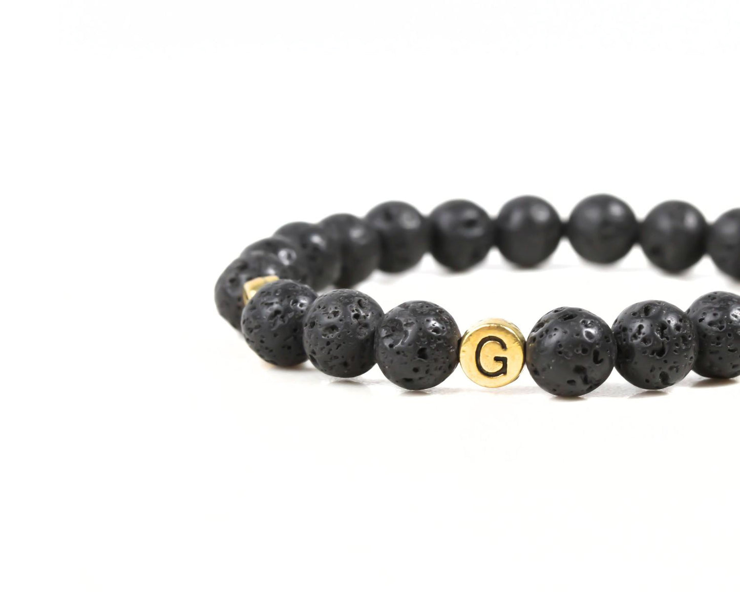 A bracelet made of black beads with a gold letter "G" on it.