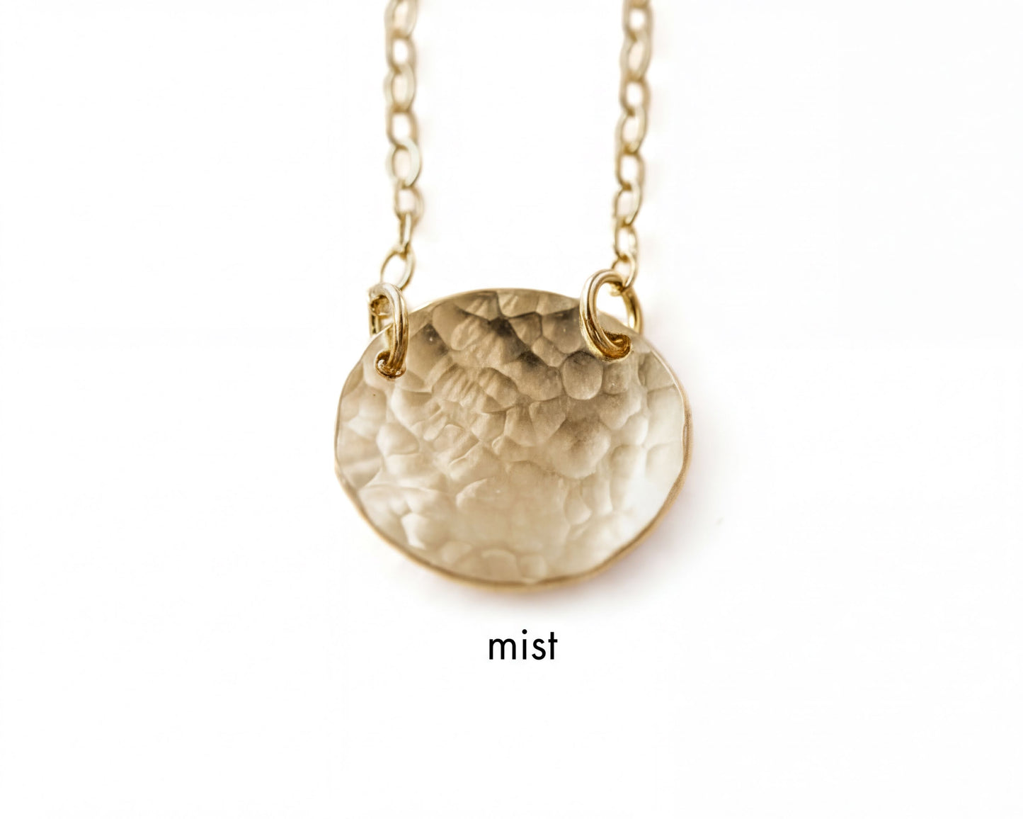 A gold-colored necklace with a textured oval pendant.