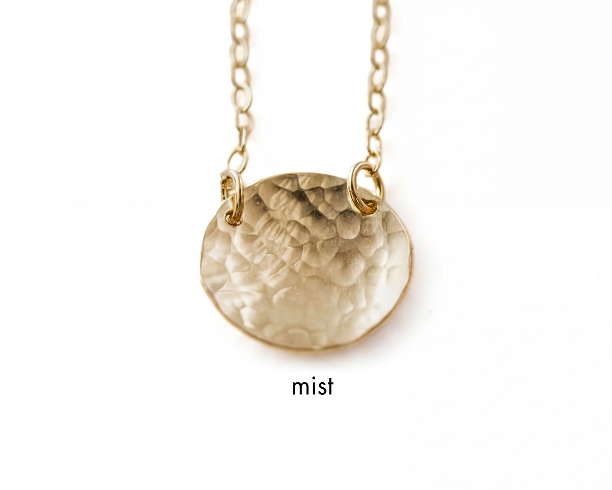 A gold-colored necklace with a textured oval pendant.