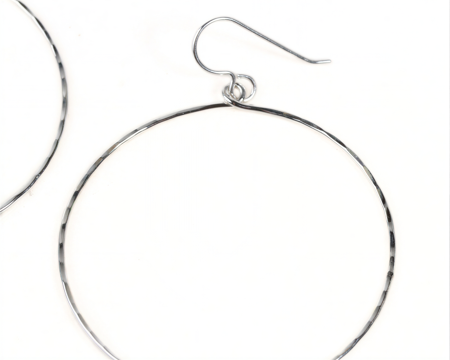 A pair of silver hoop earrings with a curved hook.