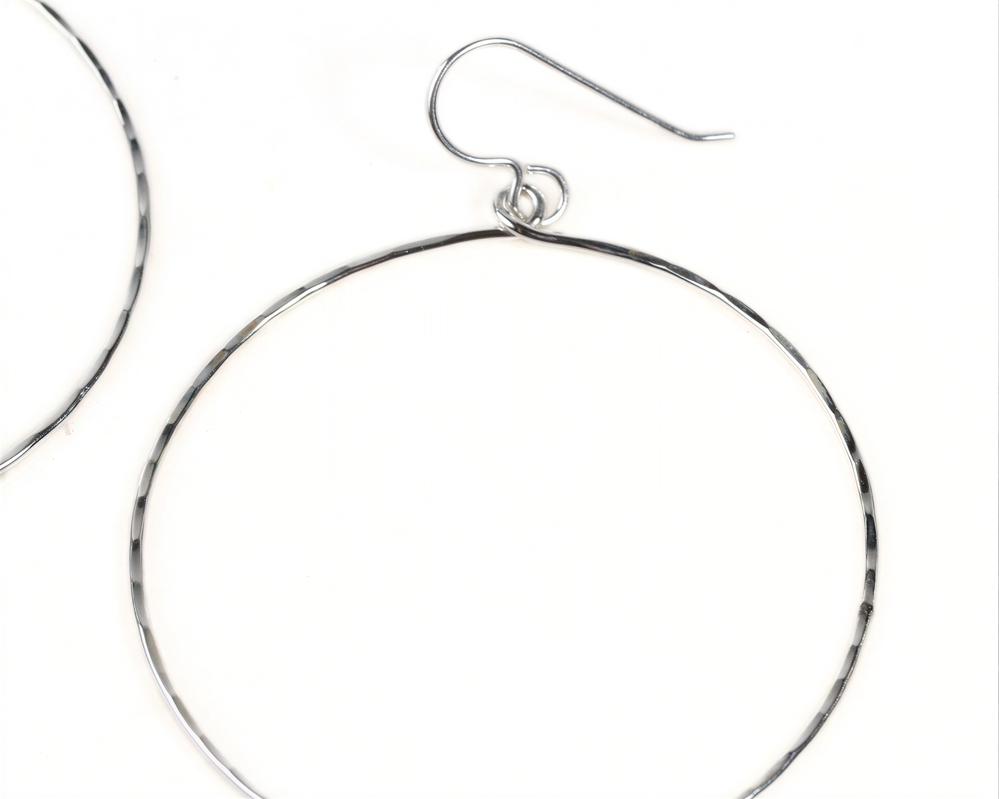 A pair of silver hoop earrings with a curved hook.