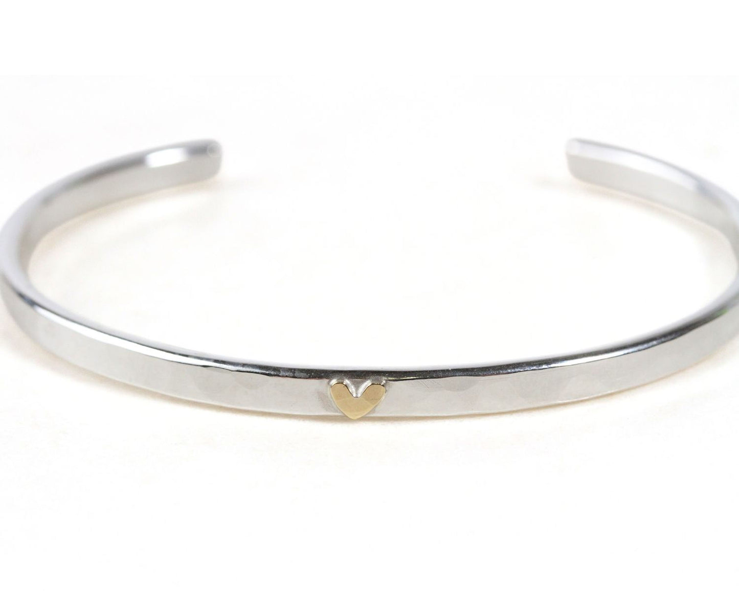 A silver bracelet with a heart-shaped charm on it.
