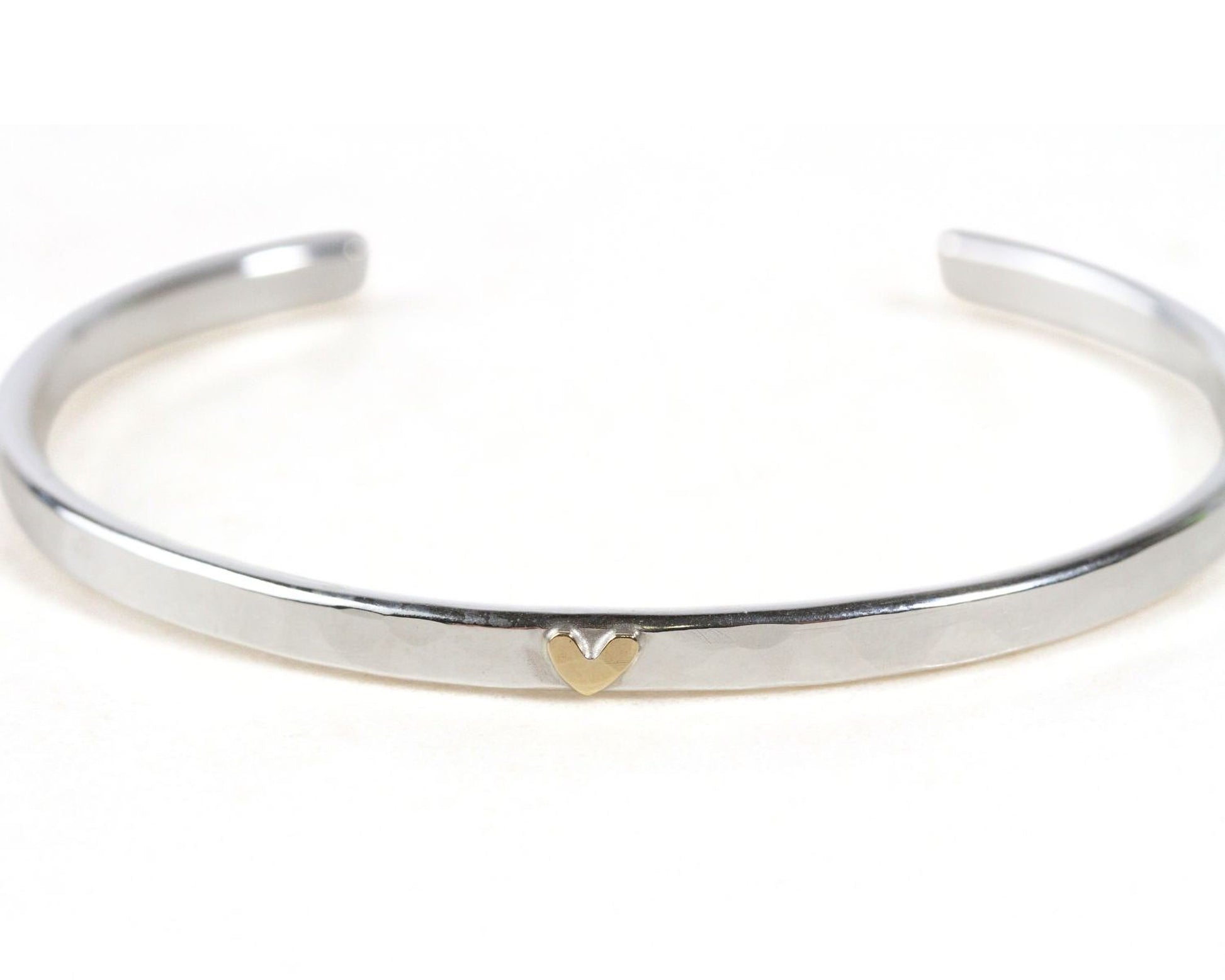 A silver bracelet with a heart-shaped charm on it.
