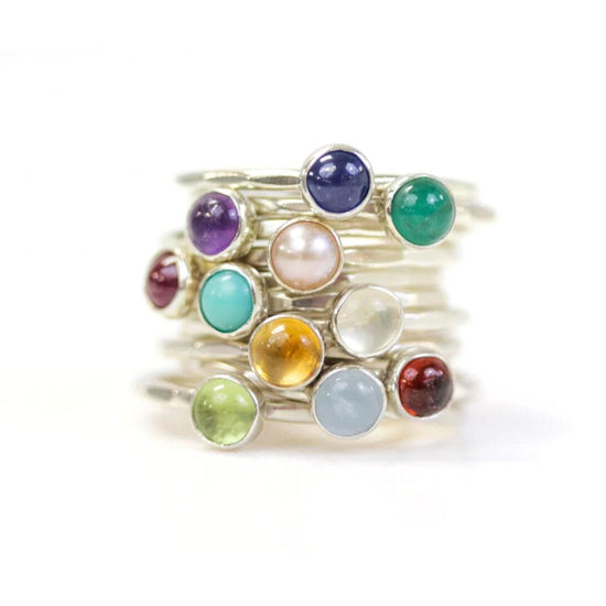 A stack of silver rings with colorful gemstones on top.