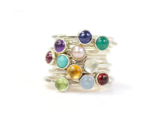 A stack of silver rings with colorful gemstones on top.