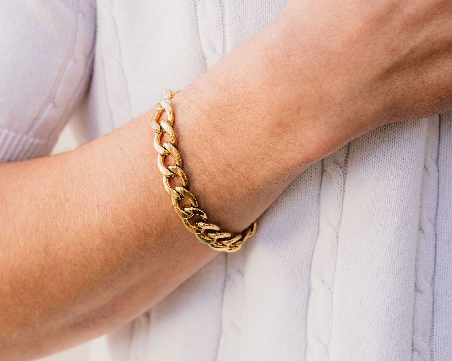 A close-up view of a person's wrist wearing a gold chain bracelet.