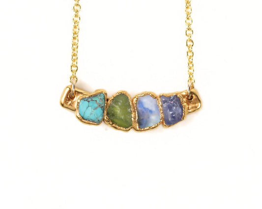 A gold necklace with a row of colorful gemstones on it.