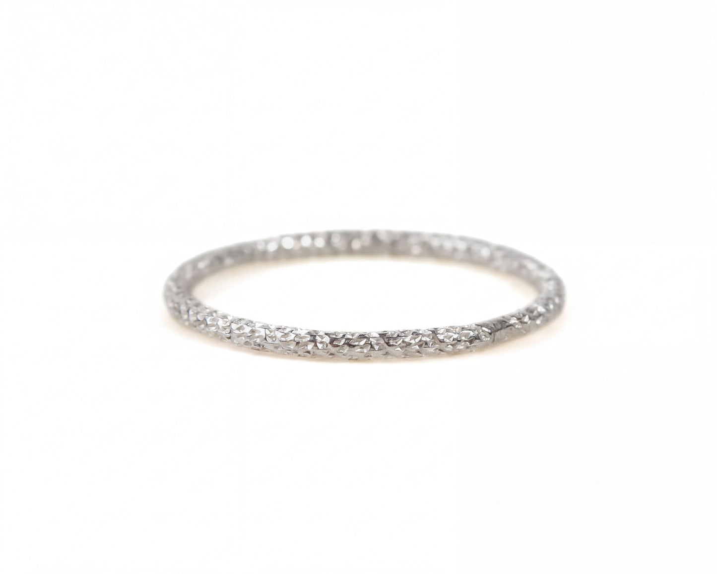 A silver ring with a textured band is shown against a white background.