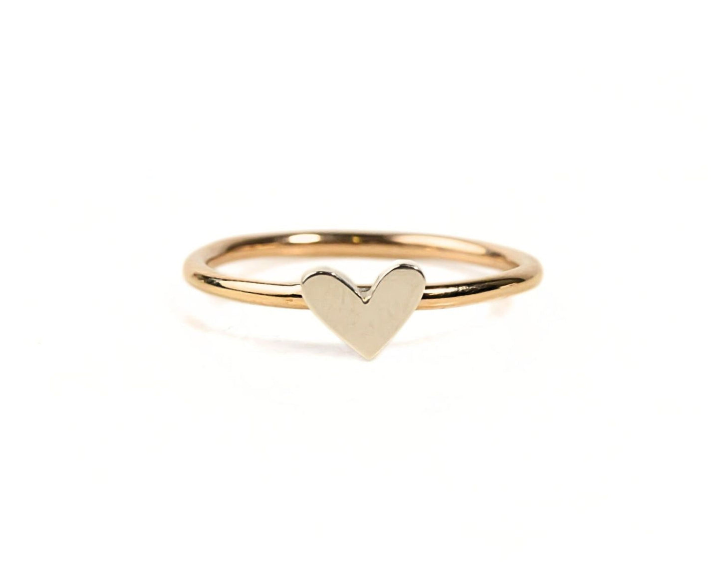 A simple gold ring with a heart-shaped charm in the center.