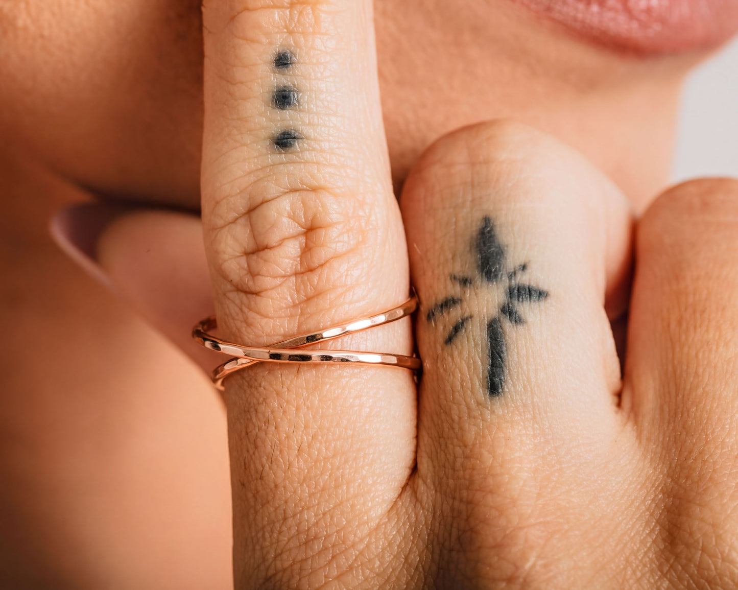 a close-up of a person's hand with two rings on the fingers and tattoos on the fingers.