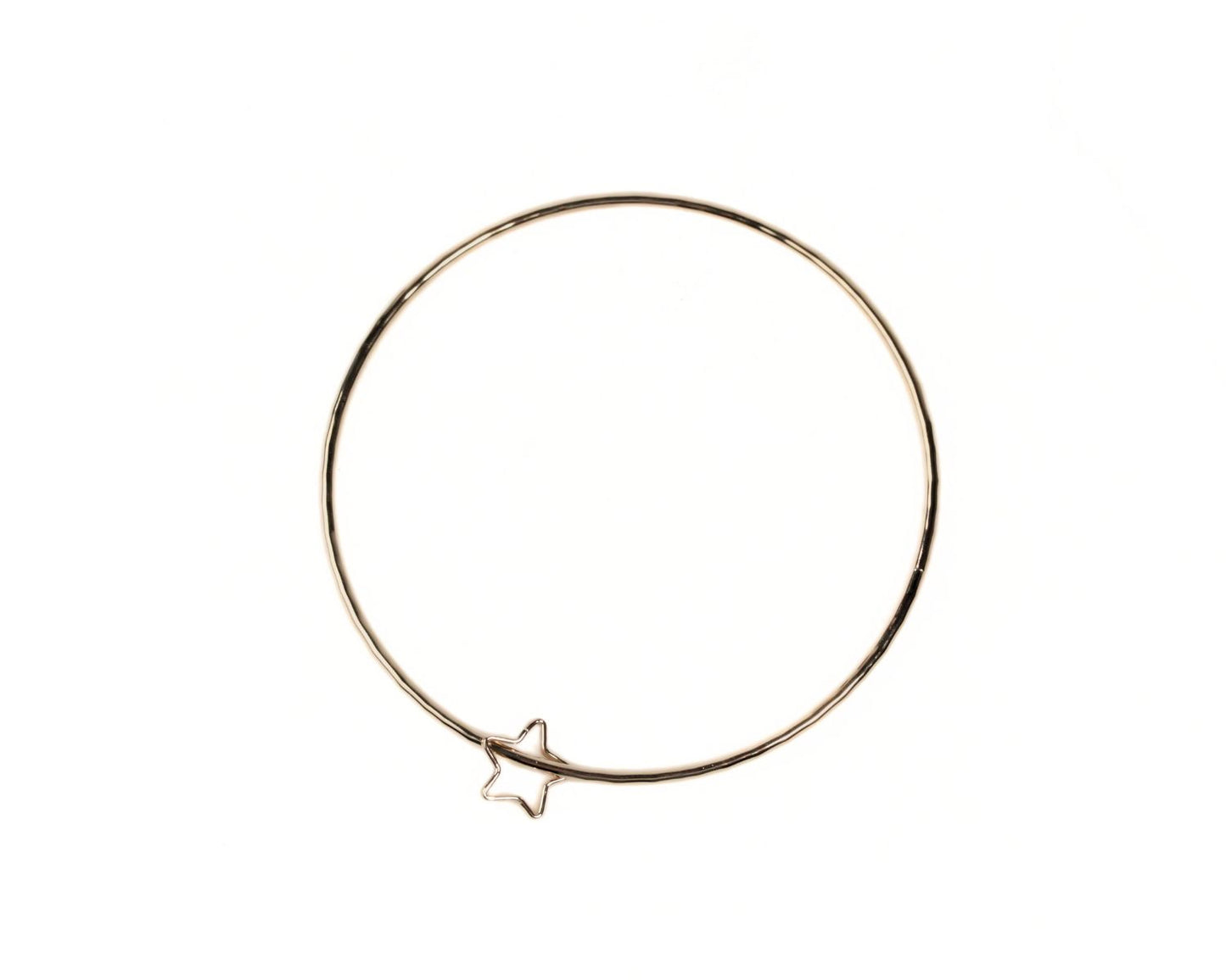 A gold-colored bangle bracelet with a small star charm attached to it.