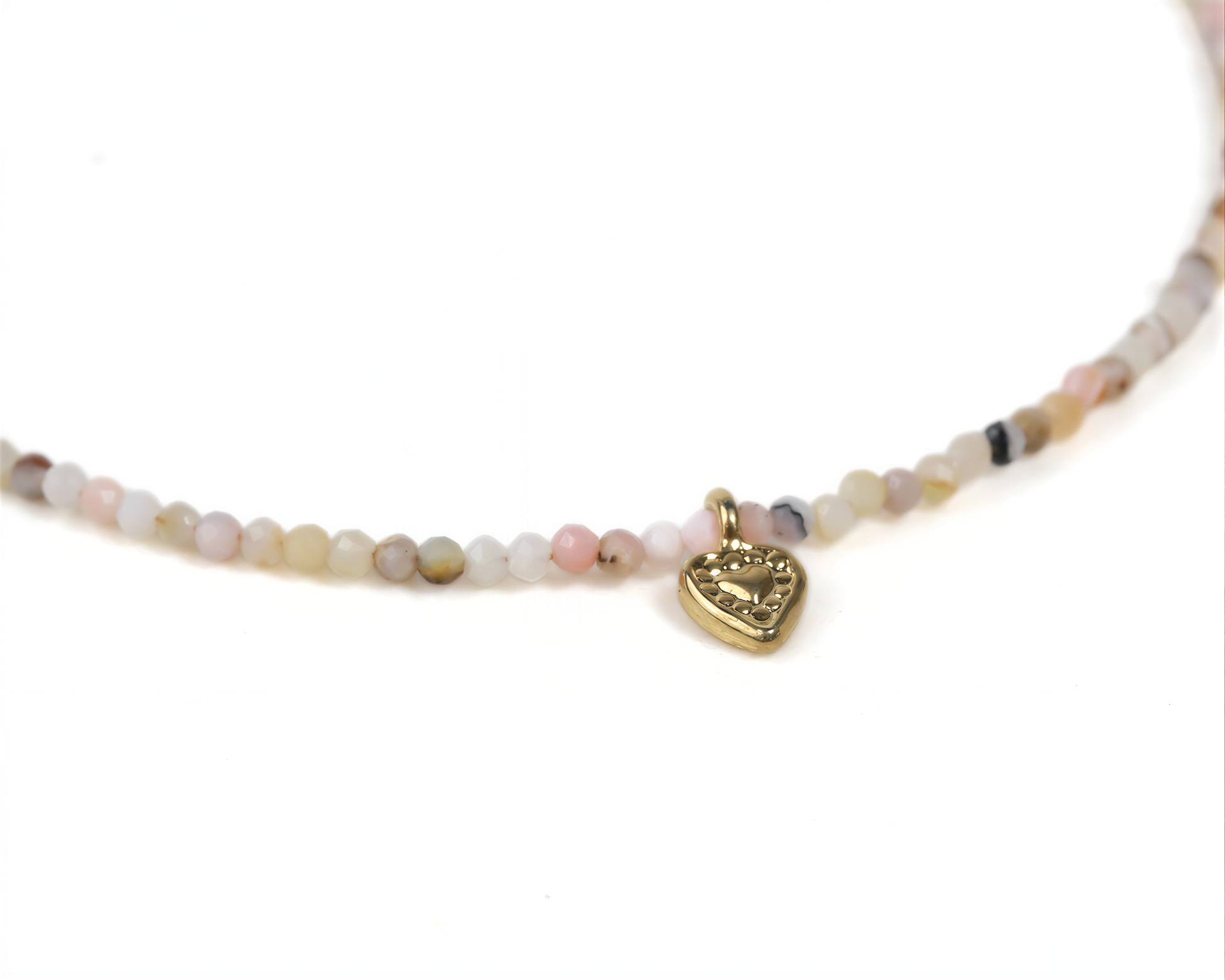 A delicate gold heart-shaped charm is attached to a delicate beaded necklace.