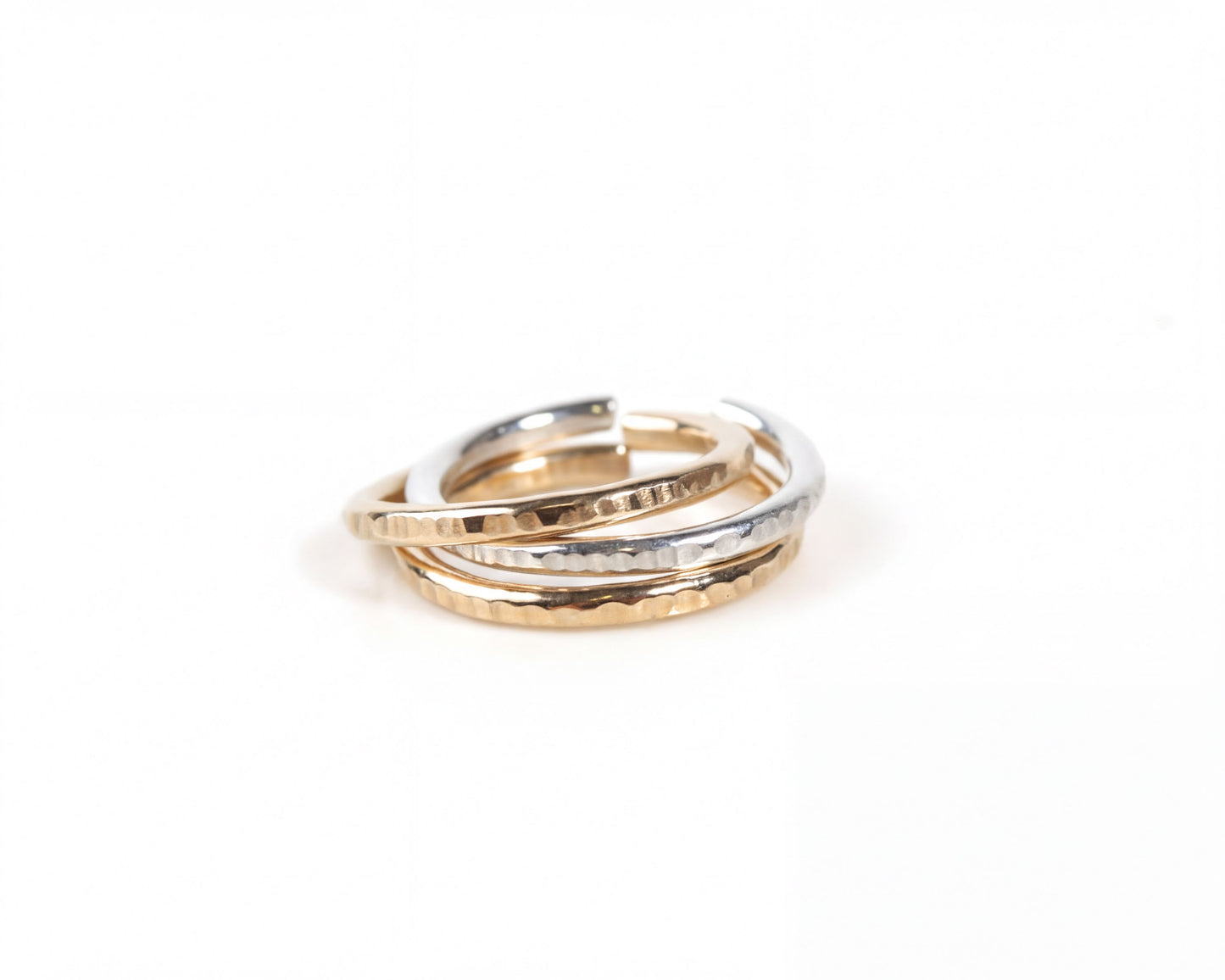 A close-up view of a stack of three rings, with the middle ring being a combination of gold and silver.