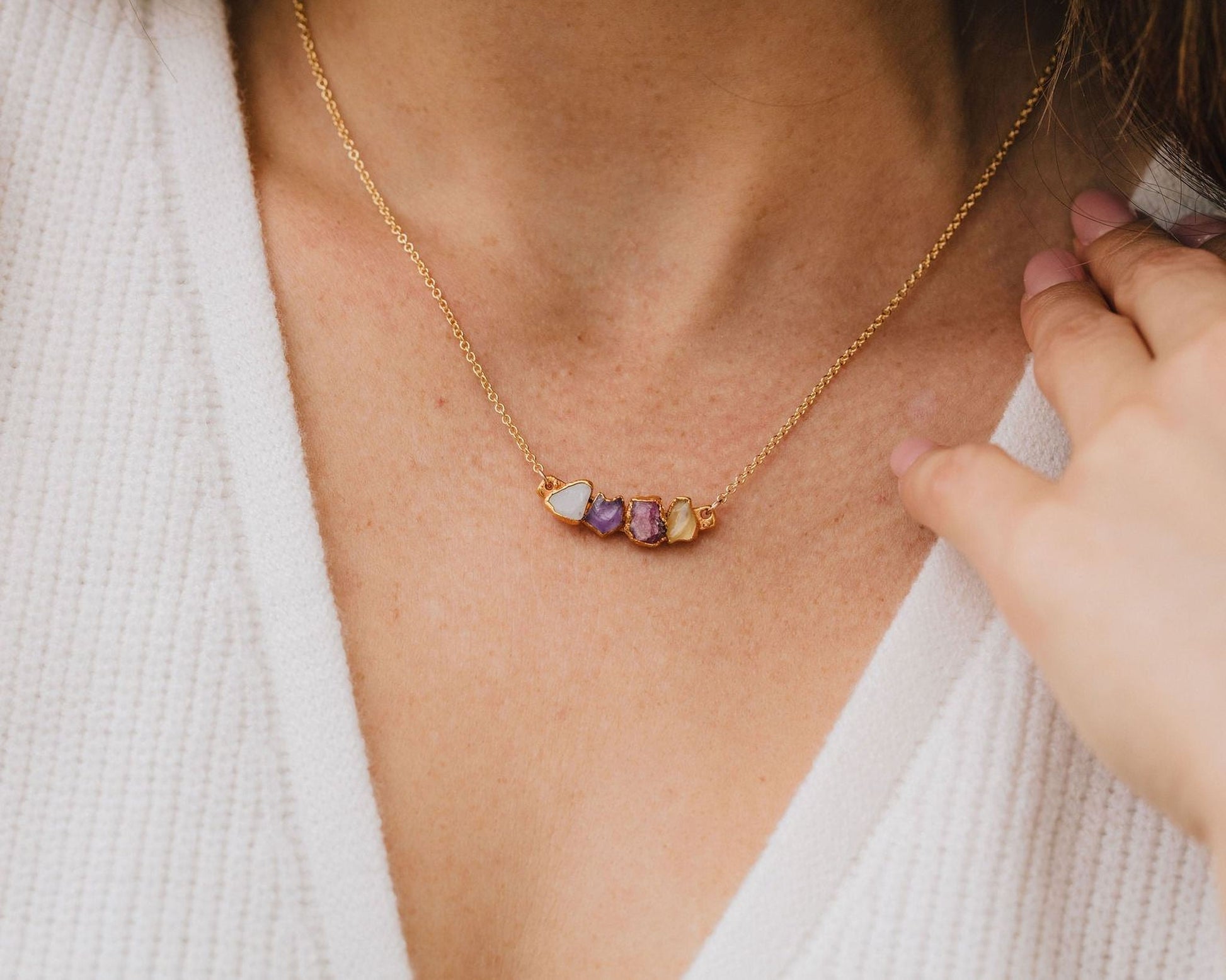 A close-up view of a gold necklace with a pendant featuring colorful stones.