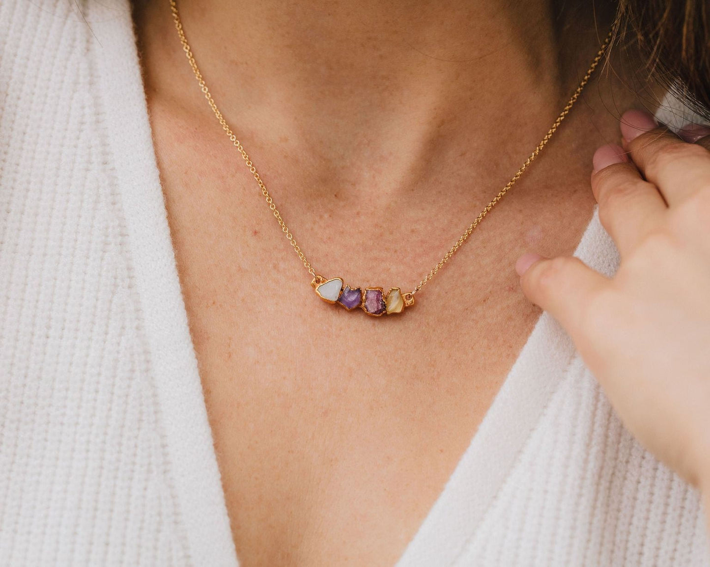 A close-up view of a gold necklace with a pendant featuring colorful stones.