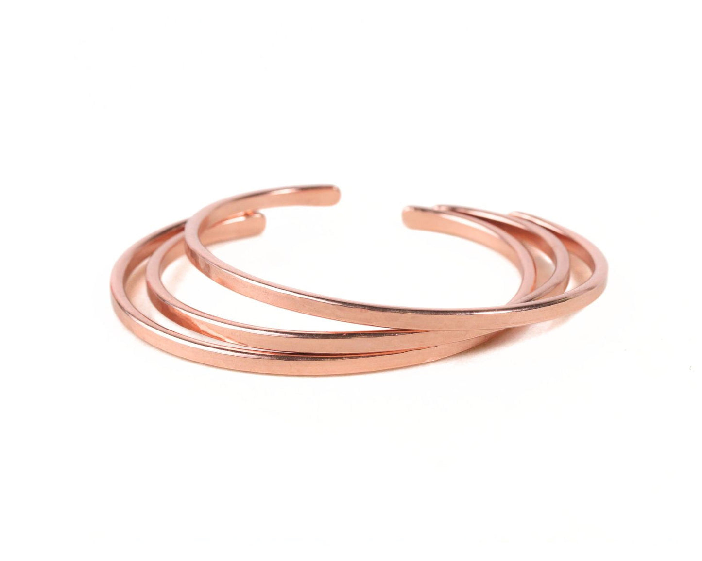 A group of copper-colored bracelets arranged in a circular pattern against a white background.