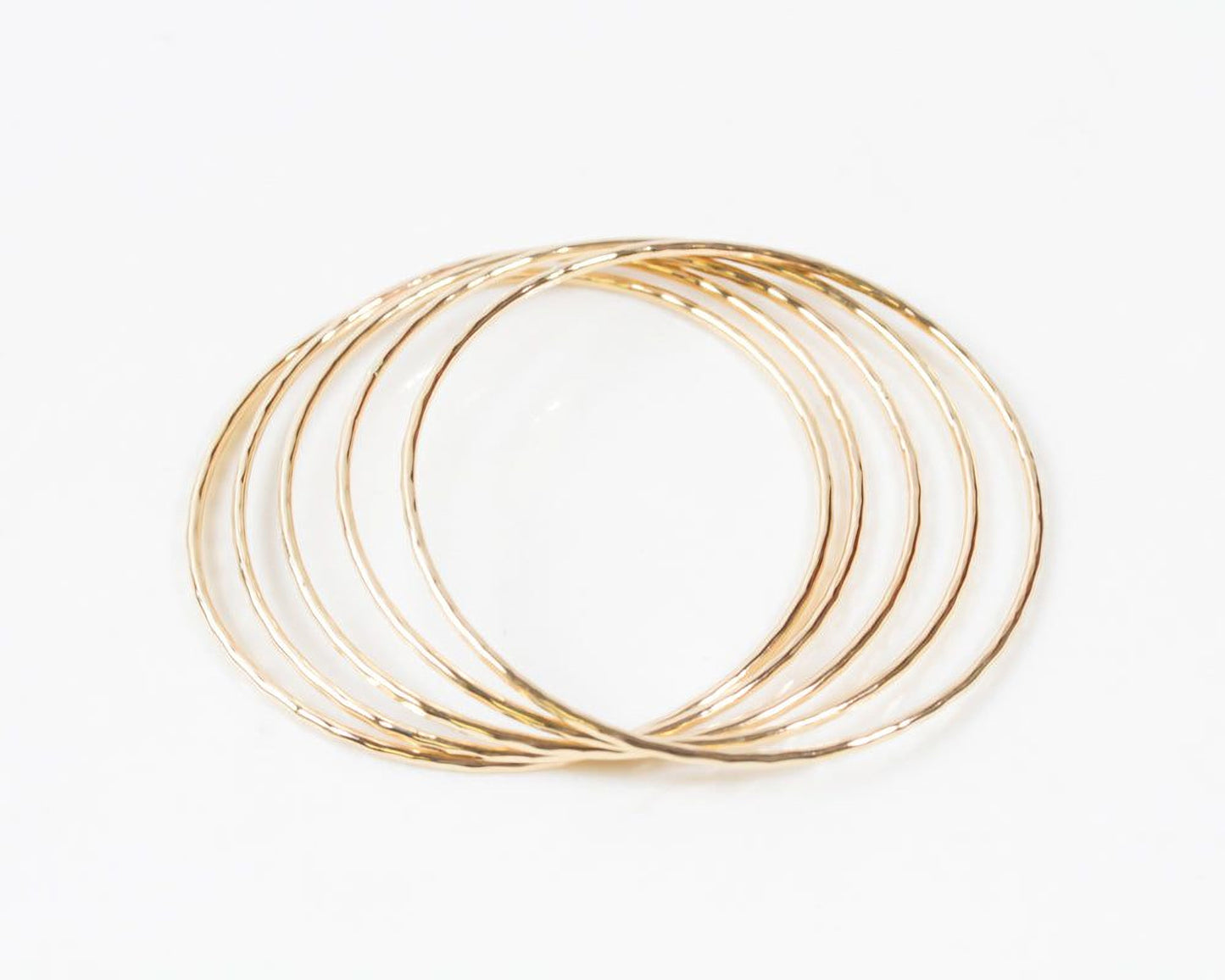 A group of gold-colored, circular bangles arranged in a circular pattern against a white background.