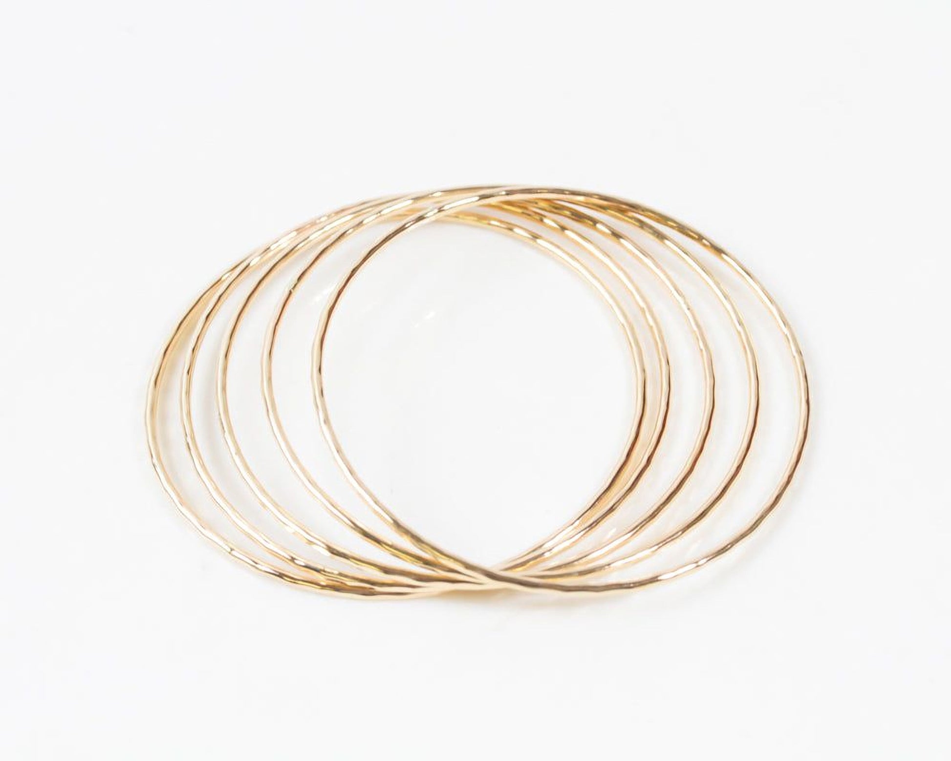 A group of gold-colored, circular bangles arranged in a circular pattern against a white background.