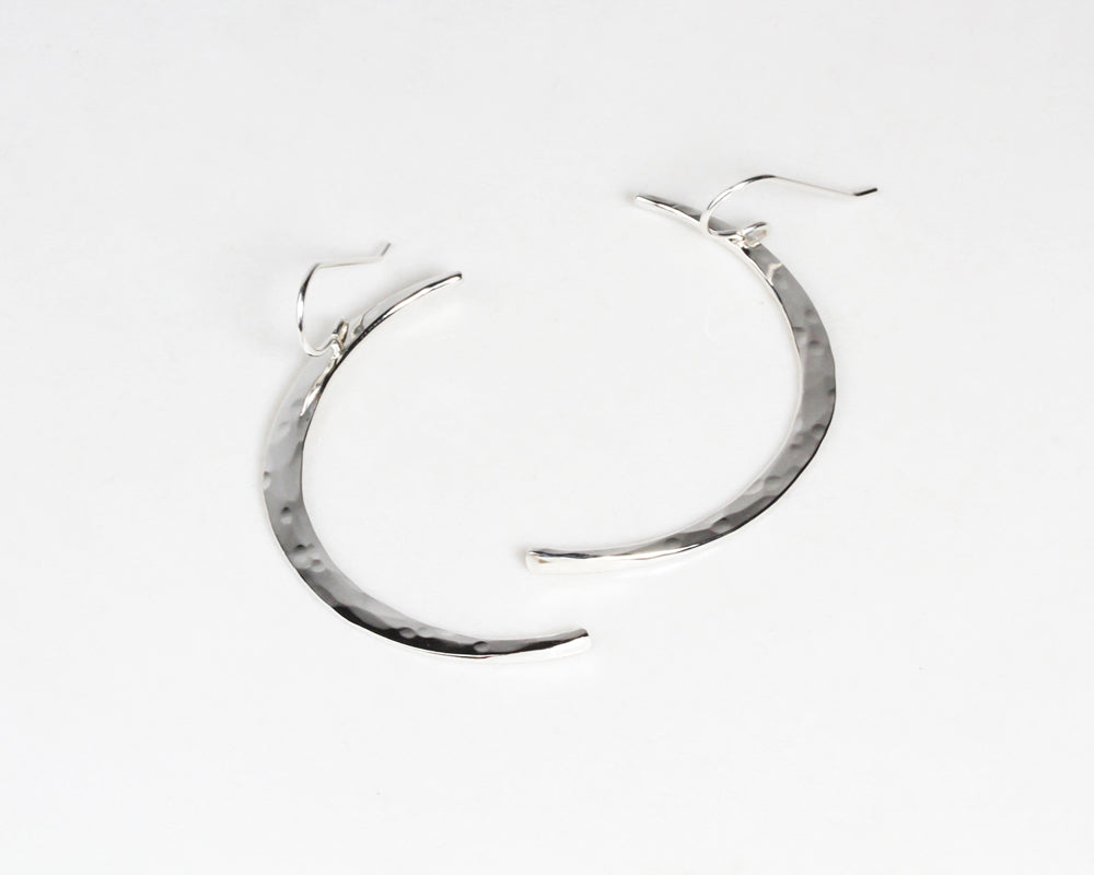 Close up shows our sterling silver moon earrings. Each moon is handmade by our team of women artists. Select your Moon Earrings in Sterling Silver or 14 Karat Yellow Gold Filled. They elevate celestial jewelry and beam with quality.