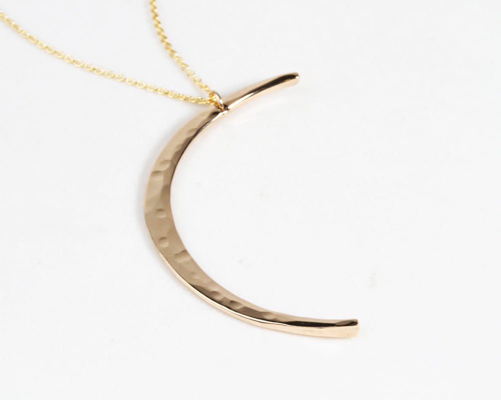 The Mystic Moon Necklace elevates celestial jewelry and beams with handcrafted quality. Each moon pendant is hand forged by our team of women artists. The crescent moon is hand hammered with texture that mimics the look of the moon and measures 44mm