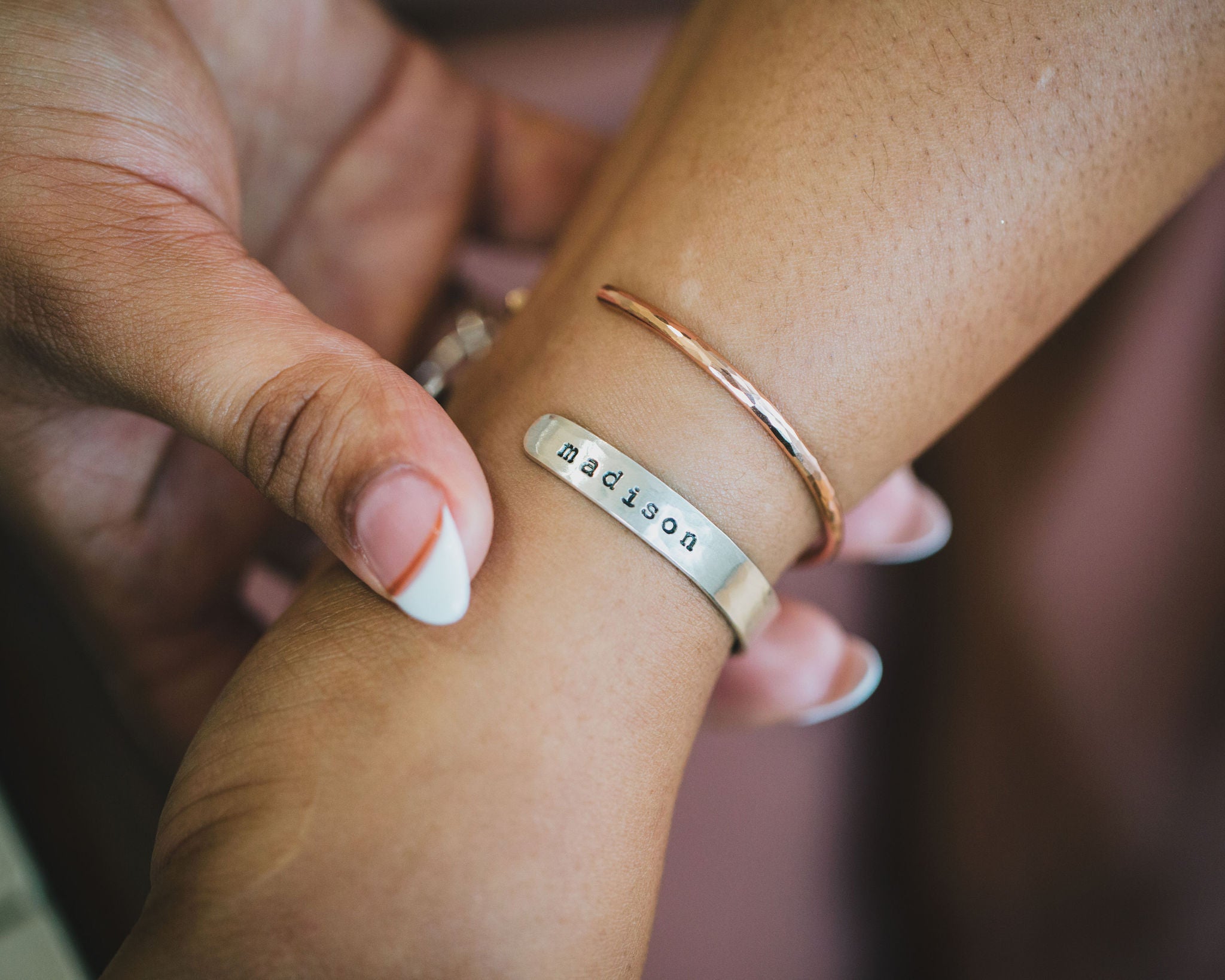 A 1/4" wide cuff in either Sterling Silver or German silver with a tiny, hand cut copper heart on the outside center. Inside the cuff reads "she believed she could so she did". The customer has the option to add a year on the inside, add a name on the outside, or add both. Paired with either a copper or rose gold filled skinny cuff that is about 1/8" wide.