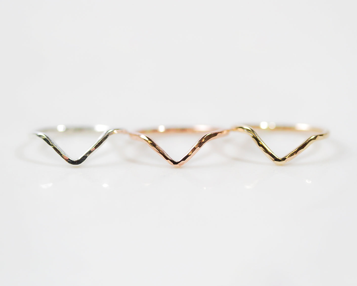 This minimalist V shaped ring is strong and bold, delicate and wearable. Image shows close up of the Chevron Ring in all metal selects, rose and gold fill and sterling silver. The ring is hand hammered which offers a delicate sparkle.